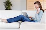 Happy young woman booking flight online on the sofa