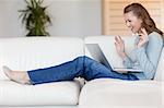 Happy smiling young woman on the sofa with her laptop