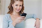 Young woman on the couch typing on her smartphone