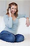 Young woman sitting on the couch answering the phone