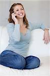 Smiling young woman on the sofa answering the phone