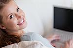 Shadowing young woman with laptop on the sofa