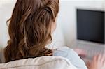 Shadowing young woman on the sofa working on her laptop