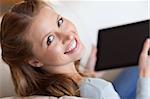 Shadowing smiling young woman on the sofa with tablet