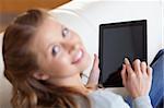 Above view of smiling young woman using tablet on the sofa