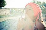 Young girl blowing soap bubbles in sun light