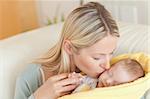 Young mother on the sofa kissing her baby