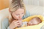 Young mother on the sofa kissing her baby's hand