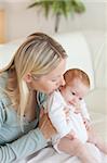 Young mother on the sofa holding her baby