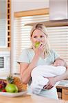 Young female with baby on her arm having an apple