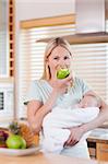 Young mother with newborn on her arms having an apple