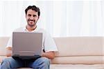 Smiling man using a laptop in his living room