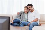 Happy couple watching TV in their living room