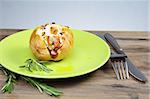 Baked potatoes with rosemary on a green plate.