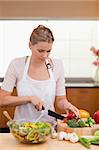 Portrait of a woman slicing vegetables in her kitchen