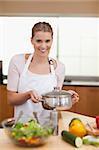 Portrait of a woman holding a sauce pan in her kitchen