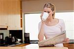Woman reading the news while having coffee in her kitchen
