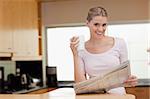 Young woman reading the news while having coffee in her kitchen