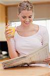 Portrait of a woman reading the news while drinking orange juice in her kitchen