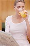 Portrait of a beautiful woman reading the news while drinking juice in her kitchen