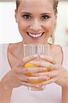 Portrait of a smiling woman drinking juice in her kitchen