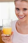 Portrait of a young woman drinking orange juice in her kitchen