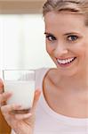 Portrait of a young woman drinking a glass of milk in her kitchen