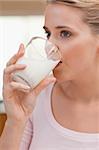 Portrait of a woman drinking a glass of milk in her kitchen