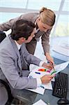 Portrait of a manager pointing at something to her employee on a graph in his office