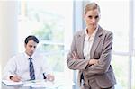 Serious businesswoman posing while her colleague is working in a meeting room