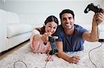 Playful young couple playing video games in their living room