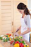 Portrait of a young woman chopping pepper in her kitchen