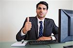 Businessman with the thumb up in his office
