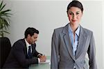 Beautiful businesswoman posing while her colleague is working in an office