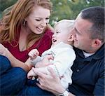 Attractive Young Parents Laughing with their Child Boy in the Park.