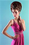 very elegant young woman wearing a pink evening dress and fashion up-do on turquoise background