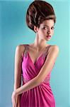 fashion shot of a gorgeous brunette with a a fashion hair up-do and wearing an elegant pink evening dress with small pearls