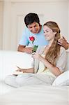 Portrait of a man offering a rose to his fiance in their living room