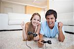 Cheerful young couple playing video games in their living room