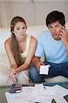 Portrait of a worried couple looking at their receipts in their living room