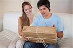 Young couple looking at a package in their living room