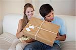 Smiling couple opening a package in their living room