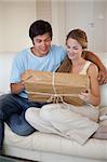 Portrait of a young couple looking at a package in their living room