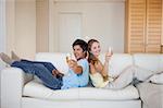 Couple sitting back to back with a glass of sparkling wine in their living room