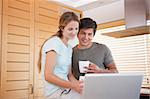 Couple having tea while using a notebook in their kitchen