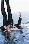 Portrait of a cheerful businessman falling into water with the thumb up