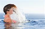 Young woman raising her head out of the water in a swimming pool