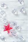 christmas red crystal star over ice cubes and white fur background