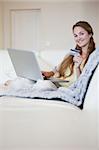 Young woman on the sofa booking a flight online