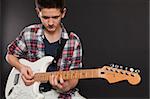 Photo of a teenage male playing a white electric guitar.